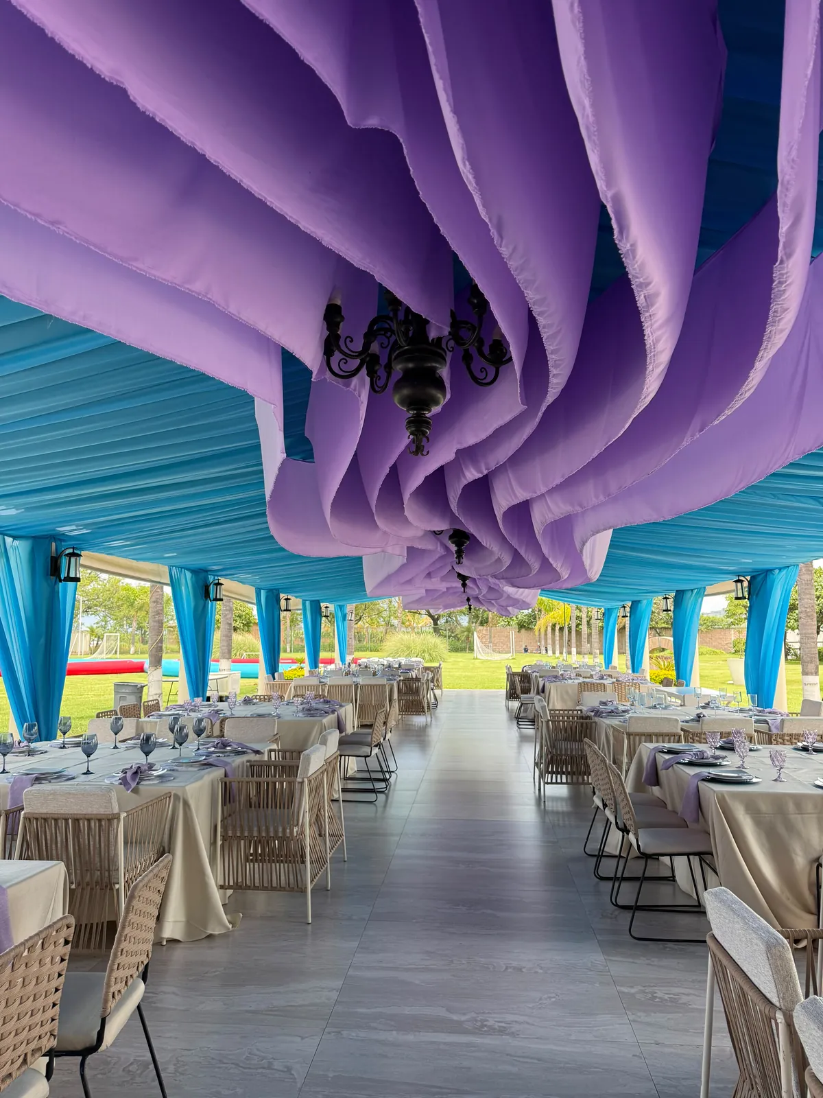 Cortinaje violeta con candil sobre techo turquesa en un salón de eventos
